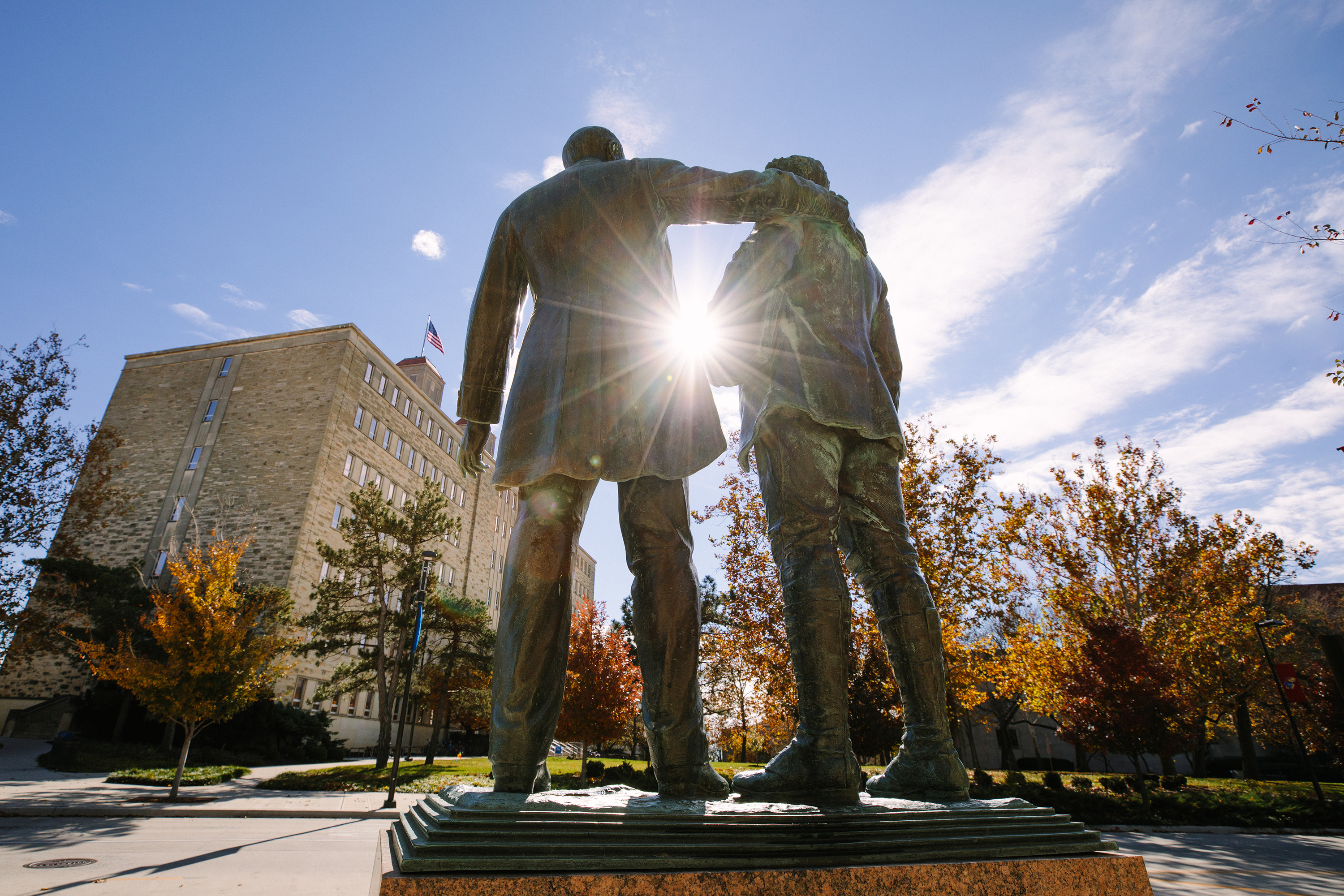 Statue outside Fraser Hall with trees and blue sky